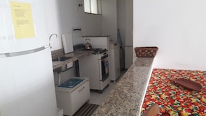 A small kitchenette with a refrigerator, sink, stove, and a microwave. - Fully furnished apartment with excellent location: Airport, beaches, and city center. (Ilhéus)