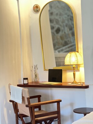 Uma cadeira de madeira com uma toalha, um laptop numa mesa, uma lâmpada e um espelho.