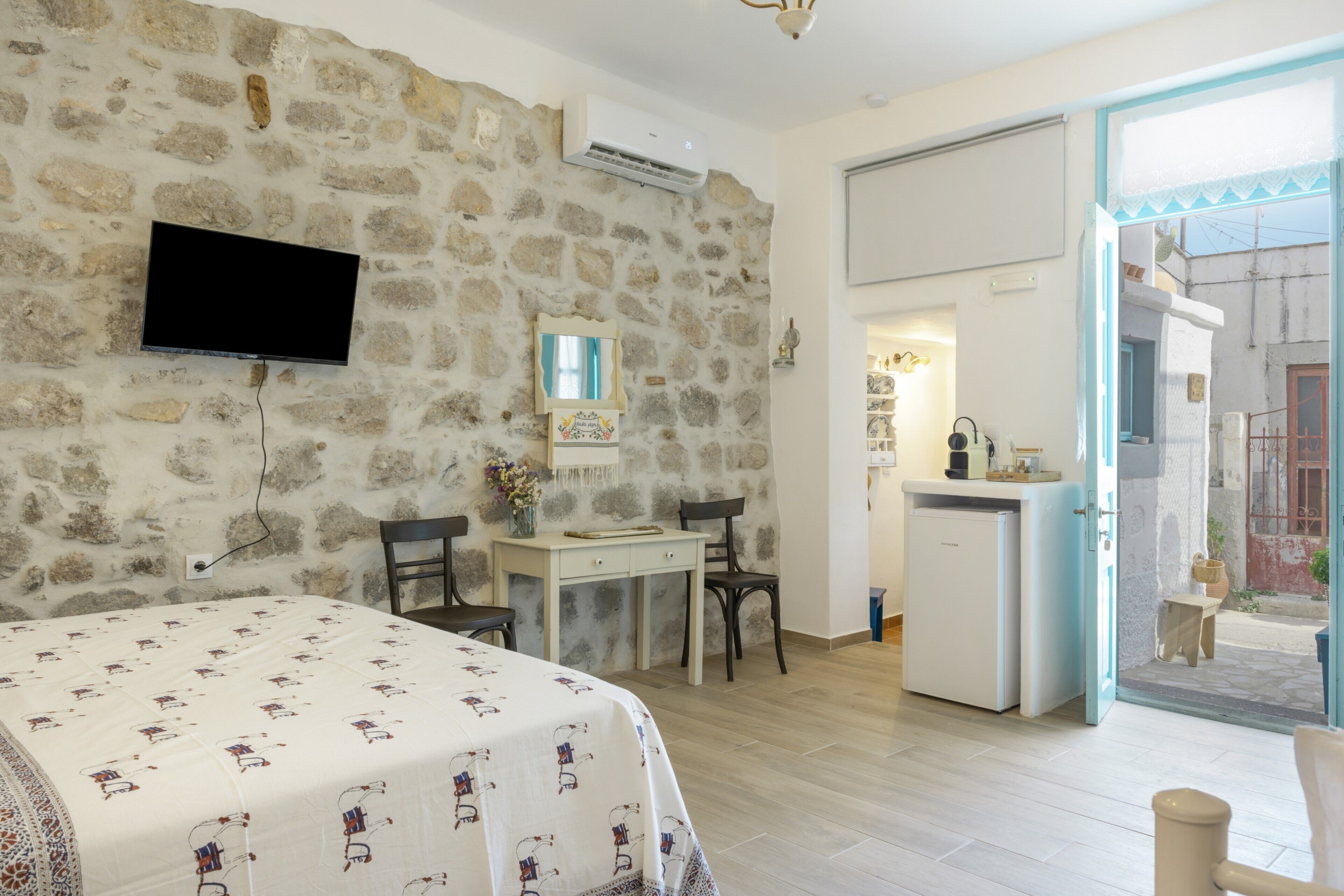 Une chambre comprenant un lit, un bureau, des chaises, une télévision et une petite kitchenette.