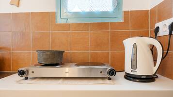 A kitchen with a stove, a kettle, and a window with a decorative frame.