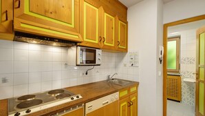 A kitchen with wooden cabinets, a microwave, a stove, and a dishwasher. - Apartment '7 Residence Ciasa Ulli Typ A' with Mountain View, Shared Terrace and Wi-Fi (San Cassiano)
