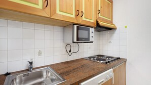 A kitchen with wooden cabinets, a microwave, a sink, and a dishwasher. - Apartment '6 Residence Ciasa Ulli Typ A' with Mountain View, Shared Terrace and Wi-Fi (San Cassiano)