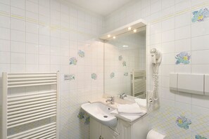 Ein Badezimmer mit weißem Waschbecken, Spiegel und Handtuchhalter.