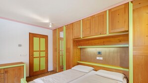 Une chambre à coucher avec un lit, une armoire en bois et une porte dotée d’un cadre vert.