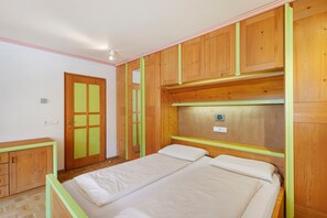 A bedroom with a bed, wooden wardrobe, and a door with a green frame. - Apartment 'Residence Ciasa Ulli Typ B' with Wi-Fi (San Cassiano)