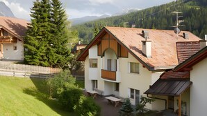 A mountain resort with chalet-style buildings, a wooden fence, and a view of the surrounding forest and mountains. - Apartment 'Residence Ciasa Ulli Typ B' with Wi-Fi (San Cassiano)