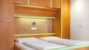 A wooden bunk bed with a green frame, a small electrical outlet, and a light switch on the wall. - Apartment 'Residence Ciasa Ulli Typ B' with Wi-Fi (San Cassiano)