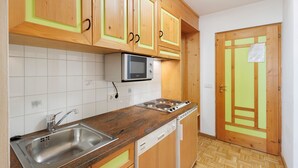 A kitchen with wooden cabinets, a microwave, a stove, a sink, and a dishwasher. - Apartment 'Residence Ciasa Ulli Typ B' with Wi-Fi (San Cassiano)