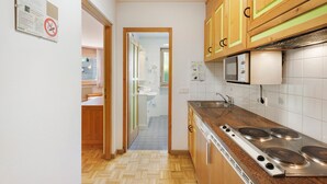 Une cuisine avec des meubles de rangement en bois, un four à micro-ondes, une cuisinière et un évier.