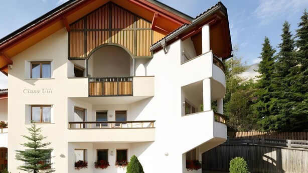 A multi-story building with balconies, a wooden facade, and a name 'Cîasa Uli' on the side. - Apartment '1 Residence Ciasa Ulli Typ B' with Mountain View, Shared Terrace and Wi-Fi (San Cassiano)