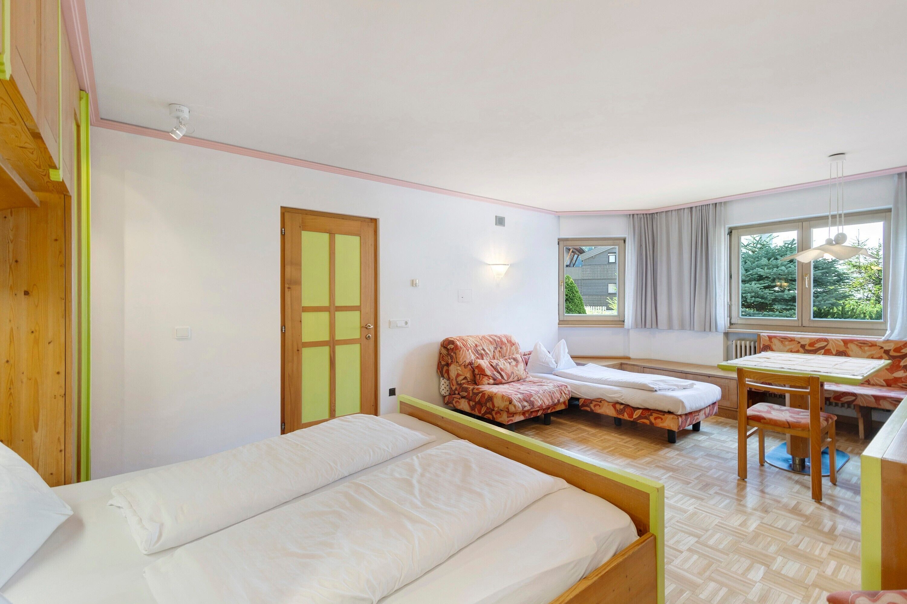 A room with two beds, a sofa, a table, and a window with a view.