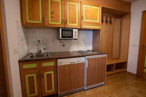 Eine Küche mit Holzschränken, einer Mikrowelle, einem Geschirrspüler und einem Herd.