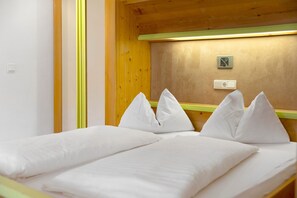 A single bed with white bedding and pillows in a room with wooden walls and a green trim. - Apartment '1 Residence Ciasa Ulli Typ B' with Mountain View, Shared Terrace and Wi-Fi (San Cassiano)