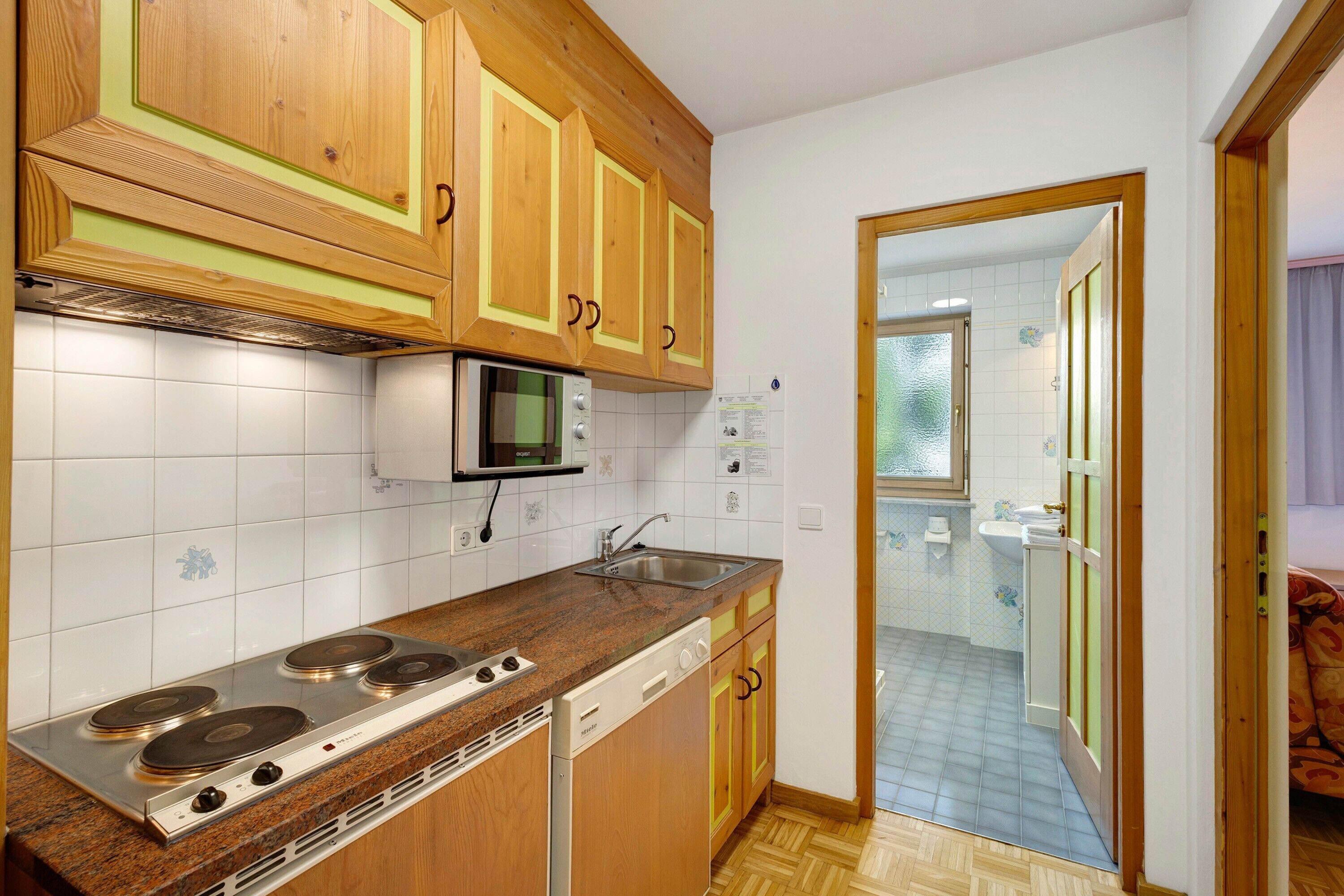 A compact kitchen with wooden cabinets, a microwave, a stove, and a dishwasher.