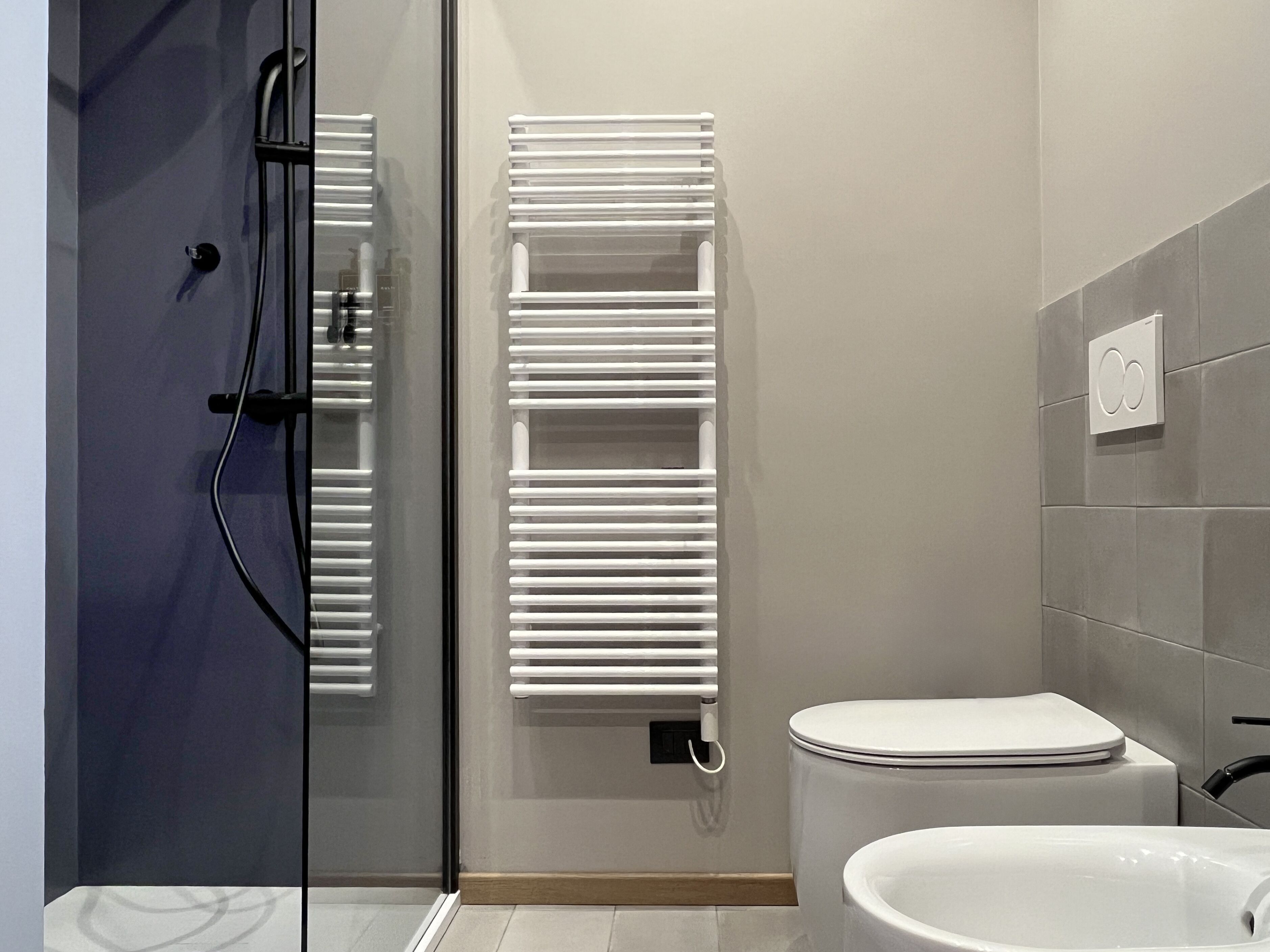 Un bagno moderno con box doccia in vetro, un water bianco e un porta asciugamani bianco.