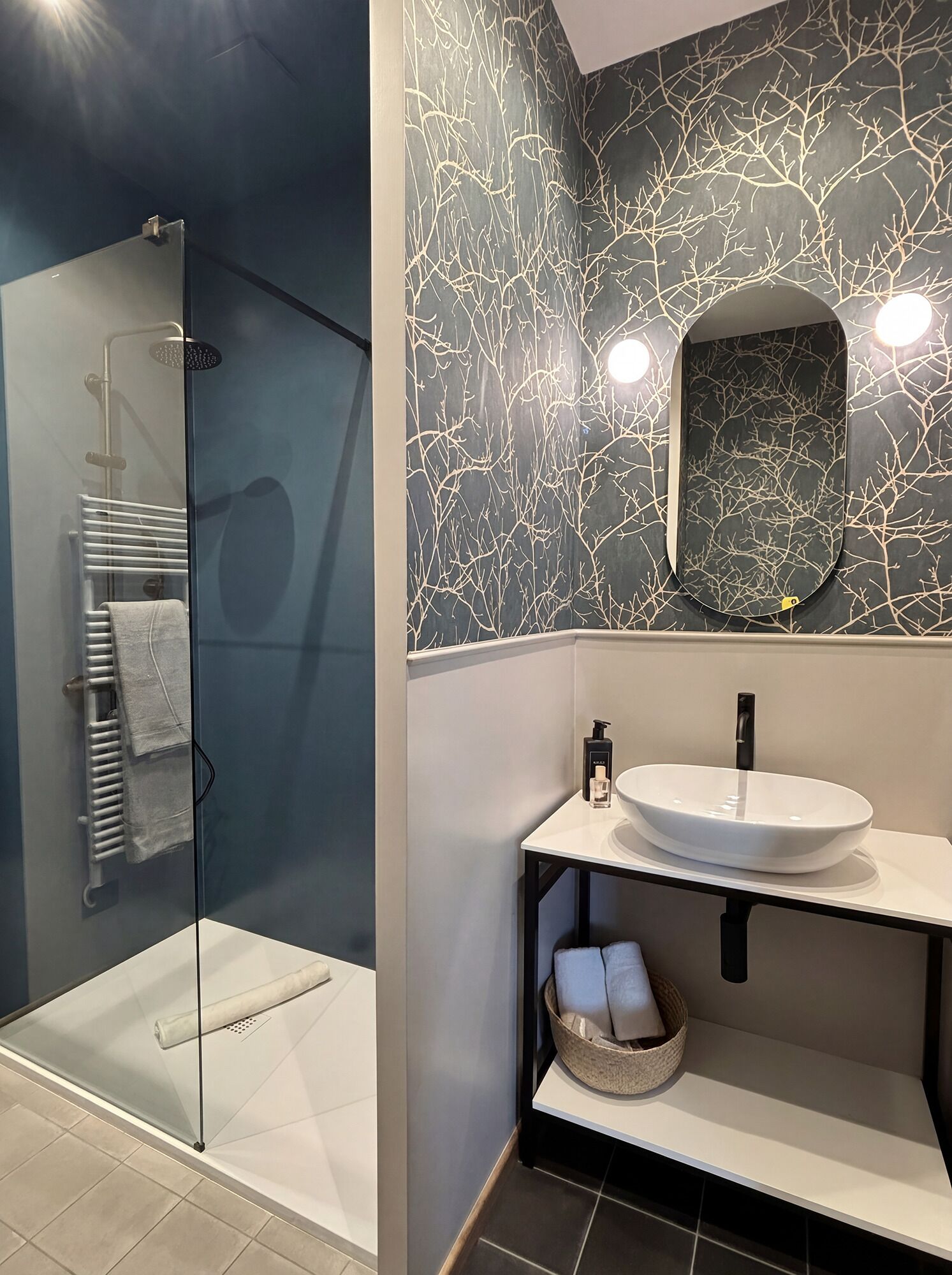 A modern bathroom with a glass shower enclosure, a white sink with a black faucet, and a wall-mounted mirror.
