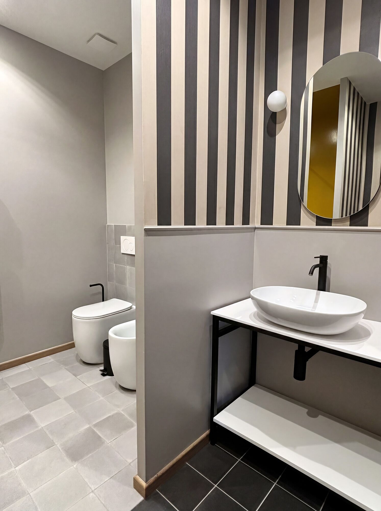Moderni kylpyhuone, jossa on wc, bidee ja peilillä varustettu pesuallas.