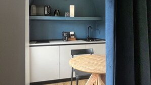 Una cocina compacta con una mesa redonda, una cafetera y un lavamanos.