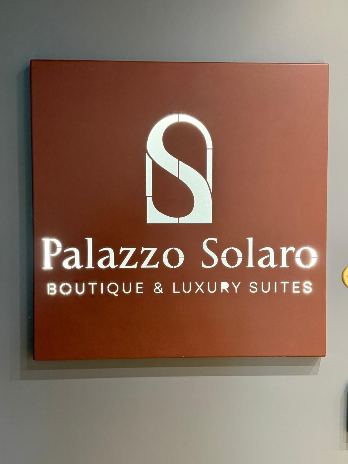 Señal para 'Palazzo Solaro Boutique & Luxury Suites' con un logotipo estilizado en forma de 'S'.
