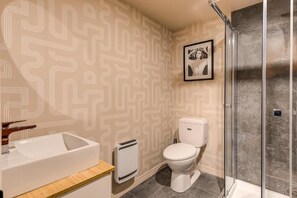 Ein Badezimmer mit modernem Design, ausgestattet mit einer Duschkabine, einer Toilette und einem Waschbecken.