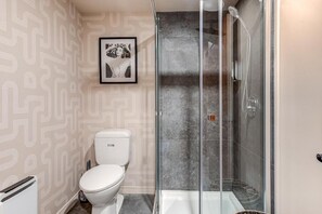 Een moderne badkamer met toilet, douchecabine en een behang met patroon.