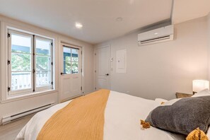 Een slaapkamer met een bed, een raam, een airconditioning en een deur.