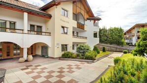 A multi-story building with a checkered courtyard, balconies, and a sign reading 'Cîasa Uli.' - Apartment 'Residence Ciasa Ulli Typ A' (San Cassiano)