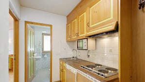 A kitchen with wooden cabinets, a built-in dishwasher, and a stove. - Apartment 'Residence Ciasa Ulli Typ A' (San Cassiano)