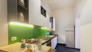 A compact kitchen with a green backsplash, a gas stove, a refrigerator, and a sink.