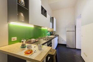 A compact kitchen with a green backsplash, a gas stove, a refrigerator, and a sink.