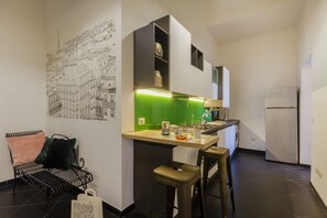 Cozinha compacta com painel verde, um banco, um assento de barra e um radiador fixado na parede.