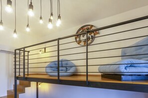 Ein Loft-Zimmer mit einer Holztreppe, einem Metallgeländer und einer runden Wanddekoration.