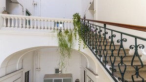 A staircase with a wrought iron railing, an archway, and a hanging plant.