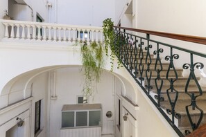 A staircase with a wrought iron railing, an archway, and a hanging plant.