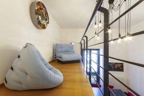 Ein modernes Interieur mit Holzboden, Sitzsack, Sofa, Weltkarte und einer Treppe mit freiliegenden Rohren.