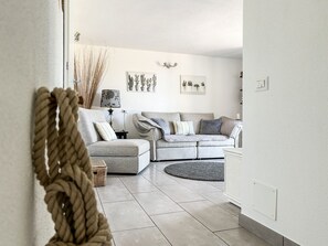 A living room with a sofa, a round rug, and wall-mounted planters. - Al CasAle - Villa in Porto Rotondo (Olbia)