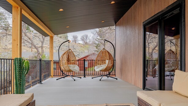 Een overdekt terras met rieten stoelen, een bank en een cactus.