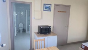A compact room with a kitchenette area, a door, and a view into the bathroom.