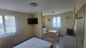 A compact room with a bed, a desk, a chair, a television, and a radiator.