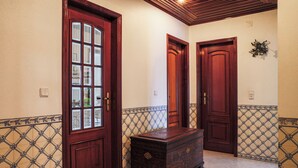 Un corridoio con tre porte in legno, un baule di legno scuro e pareti con piastrelle decorate.