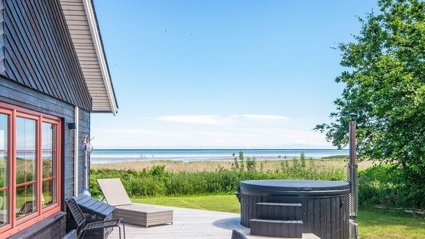 Una terraza con mesa y sillas, un jacuzzi y vista a la playa.