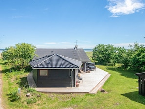 A modern house with a sloped roof, a deck, and a view of the sea. - 4 Star Holiday Home in Hadsund (Hadsund)