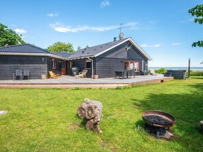 A modern house with a deck, outdoor seating, and a view of the sea. - 4 Star Holiday Home in Hadsund (Hadsund)