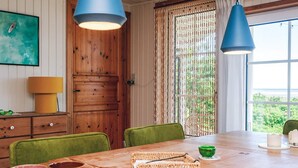 Una mesa de comedor de madera con sillas, una cesta y tazas de colores.