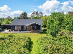A house with a covered patio, a lawn, and surrounding greenery. - 4 Star Holiday Home in Hadsund (Hadsund)