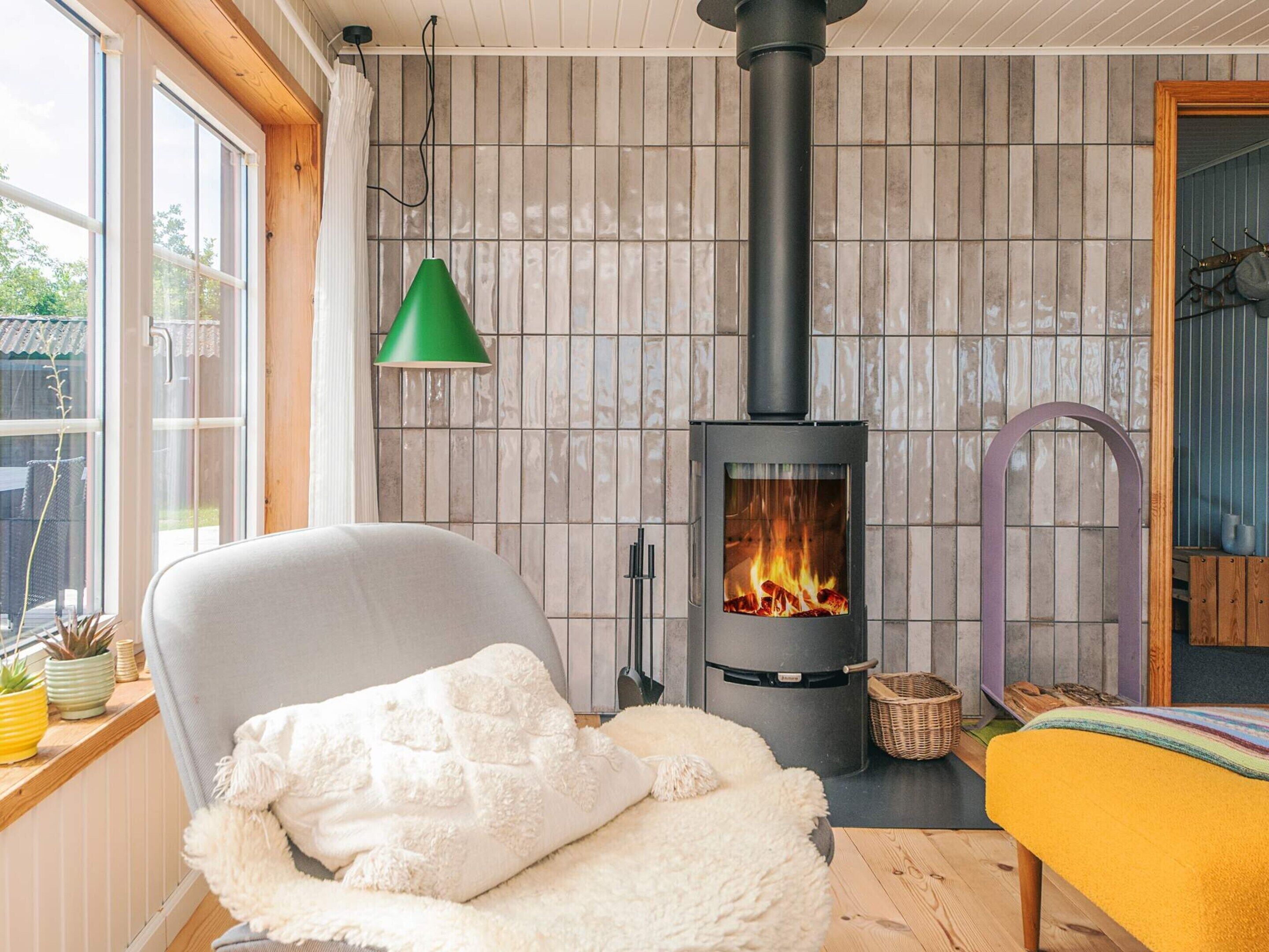 A cozy room with a wood-burning stove, a comfortable chair, and a view through a window.