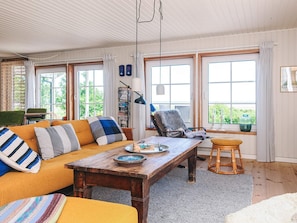 A cozy living room with a sofa, a wooden coffee table, and a wicker chair. - 4 Star Holiday Home in Hadsund (Hadsund)