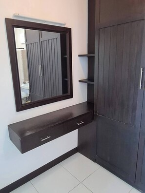 A bathroom with a dark wooden vanity, a mirror, and a cabinet.