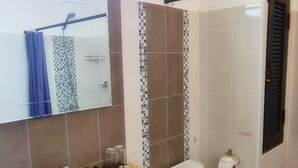 A bathroom with a sink, toilet, and shower area.