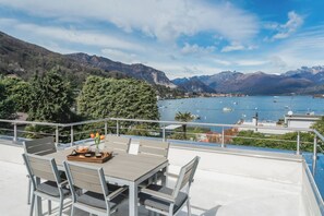 A terrace with a table and chairs overlooking a lake with boats, surrounded by mountains. - Villa Chiara - Four Bedroom Villa, Sleeps 8 (Stresa)